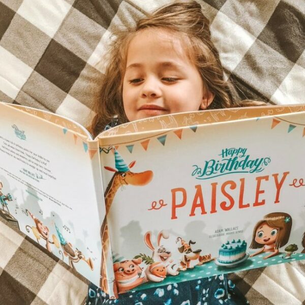 A little girl reading a personalised birthday book from Hooray Heroes.