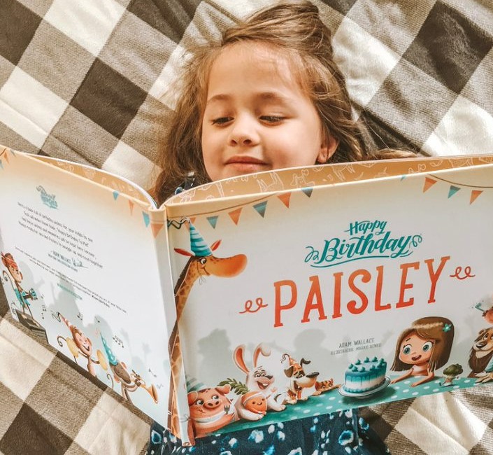 A little girl reading a personalised birthday book from Hooray Heroes.