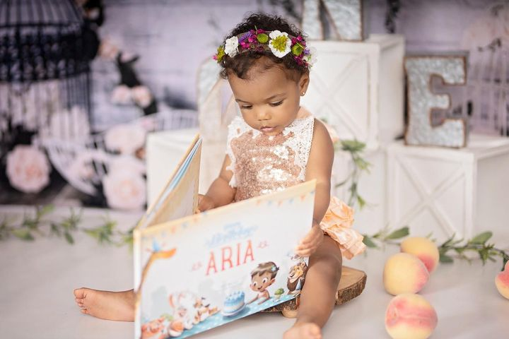 A little girl holding the personalised birthday book by Hooray Heroes.