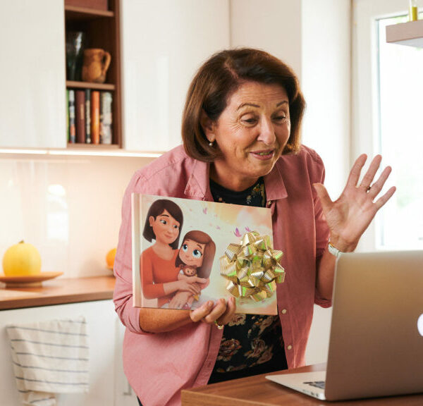 A grandmother, proudly showing her personalised book for grandparents from Hooray Heroes on a video call.