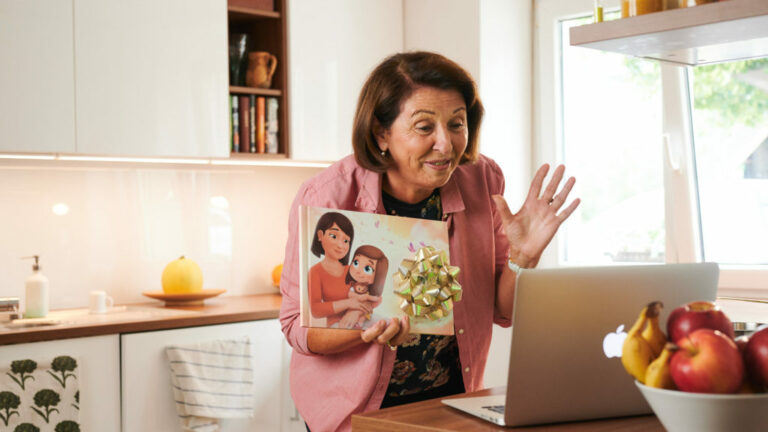 A grandmother, proudly showing her personalised book for grandparents from Hooray Heroes on a video call.